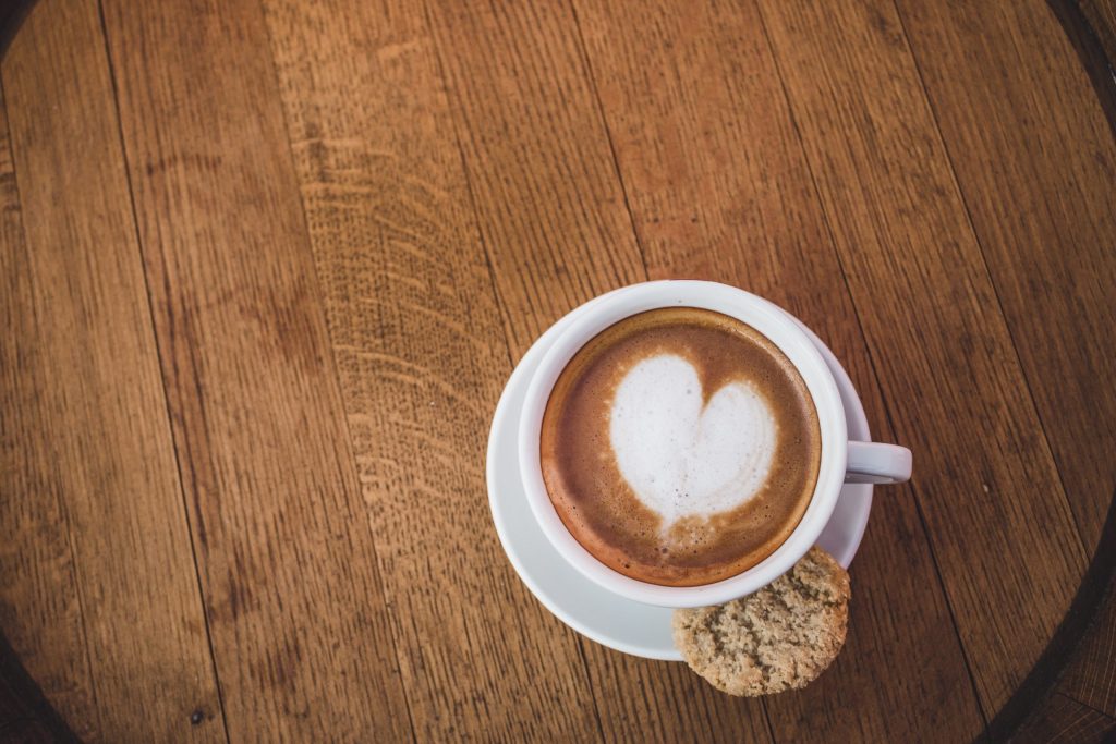 Coffee with heart in foam and biscuit