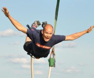 Man bungee jumping with arms out wide and smile on his face