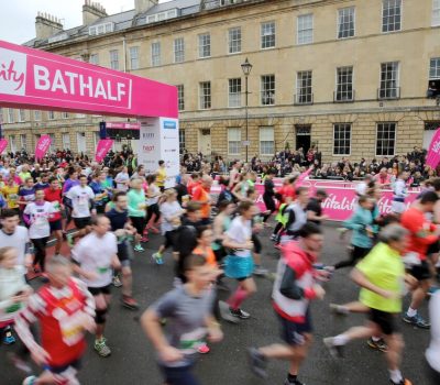 Group of runners running through start gate detailing 'Vitality Bath Half'